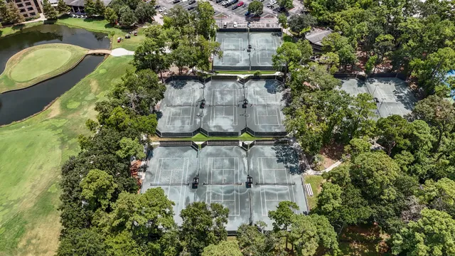 an aerial view of a house with a yard and trees all around