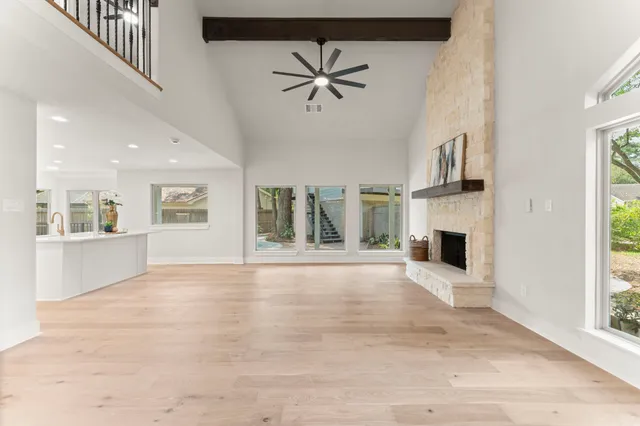 a view of an empty room with chandelier fan and windows