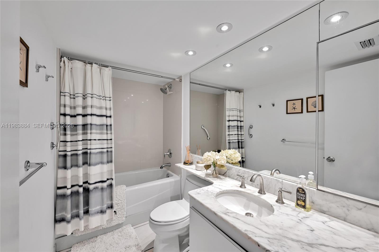 1111 Crandon Boulevard, Unit C504 Key Biscayne, FL 33149 - Photo 7 of 18 a bathroom with a granite countertop sink a toilet a mirror and shower