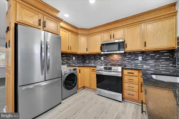 a kitchen with stainless steel appliances granite countertop a refrigerator a stove a sink and a microwave