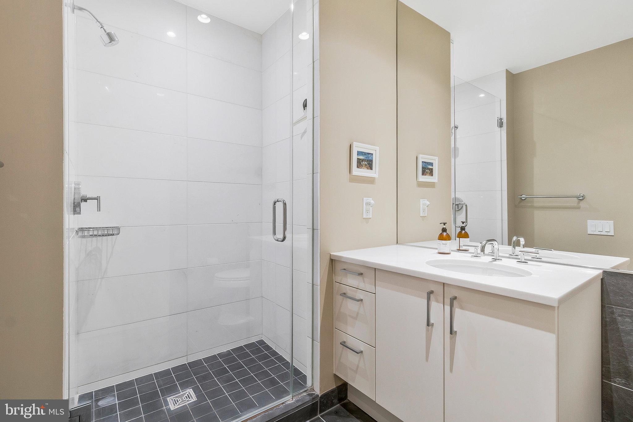 1177 22nd Street Northwest, Unit 2D Washington, DC 20037 - Photo 24 of 29 a bathroom with a sink a shower and a mirror