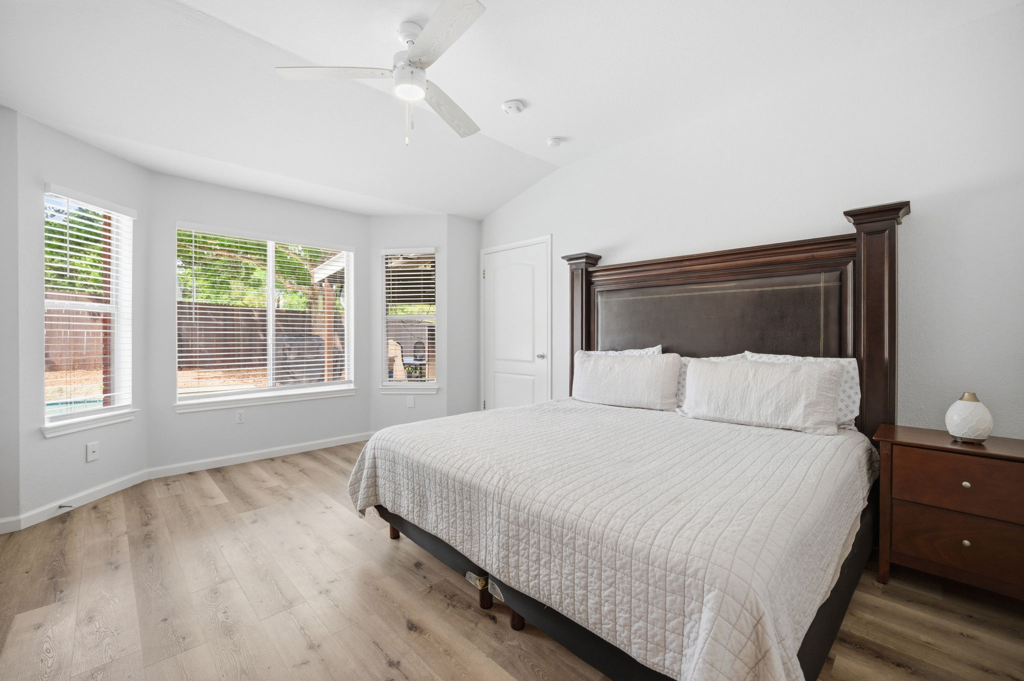 9024 Heiden Lane Austin, TX 78749 - Photo 16 of 28 Vaulted ceiling bedroom with light wood-finish flooring, a white ceiling fan, and a three-panel bay window with white blinds