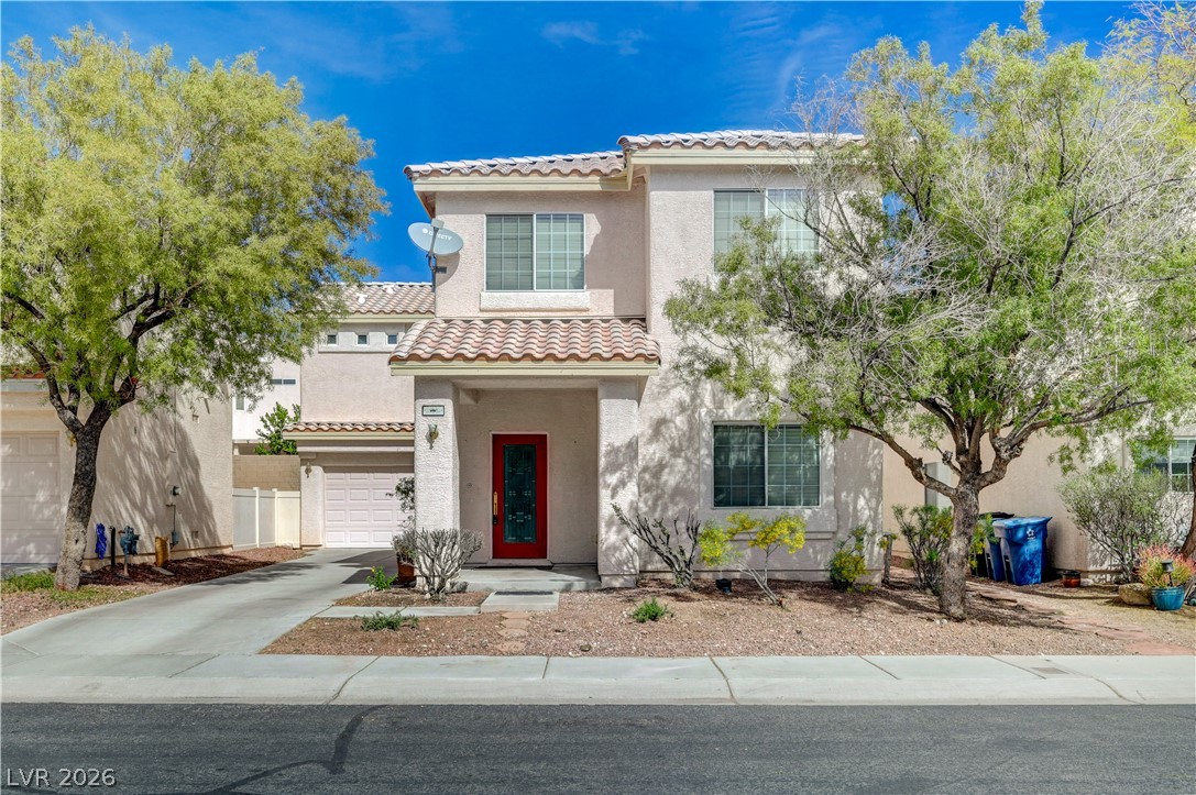 A terracotta-tiled roof crowns this residence, featuring a vibrant red front door and a well-maintained xeriscape garden.