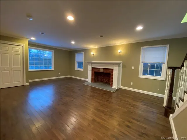 an empty room with wooden floor fireplace and windows