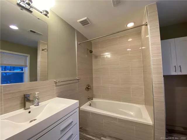 a bathroom with a bathtub shower sink vanity and toilet