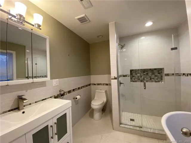 a bathroom with a granite countertop sink a toilet a mirror and shower