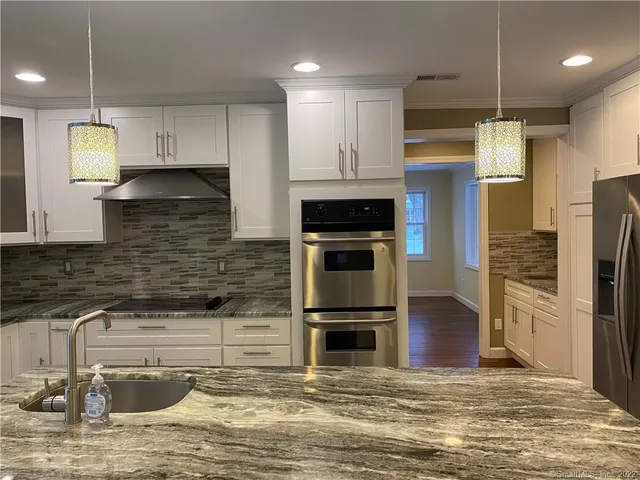 a kitchen with stainless steel appliances granite countertop a refrigerator a stove and a sink with wooden floor