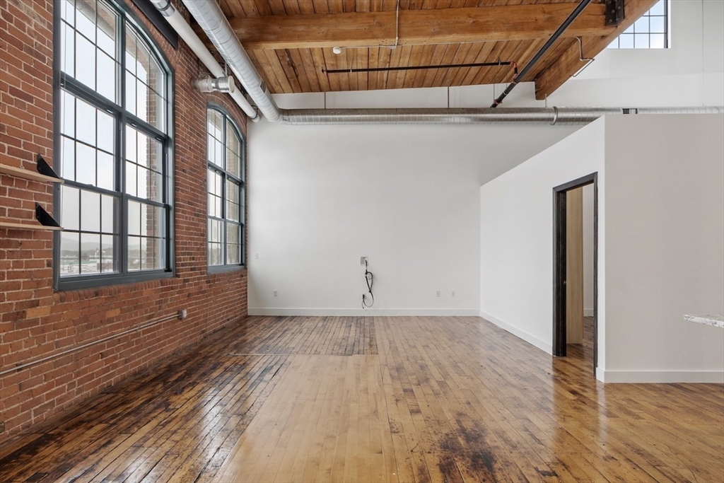 1 Westinghouse Plaza, Unit C334 Boston, MA 02136 - Photo 4 of 13 a view of an empty room with wooden floor and windows