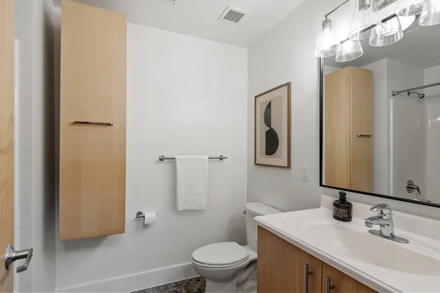 a bathroom with a granite countertop sink toilet and mirror