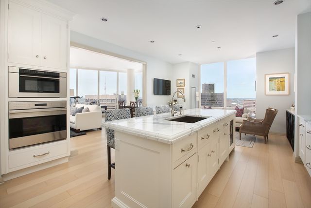 a kitchen with stainless steel appliances kitchen island granite countertop a stove top oven a sink a dining table and chairs