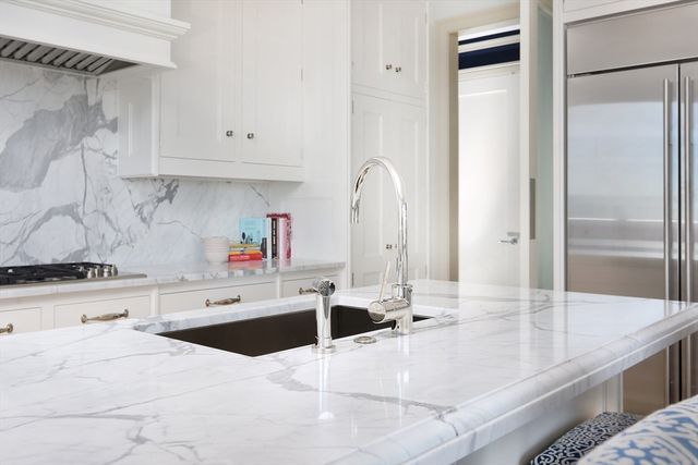 a kitchen with stainless steel appliances kitchen island granite countertop a refrigerator and a sink