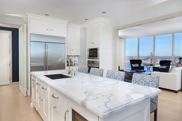 a large kitchen with kitchen island a stove a sink a refrigerator and white cabinets