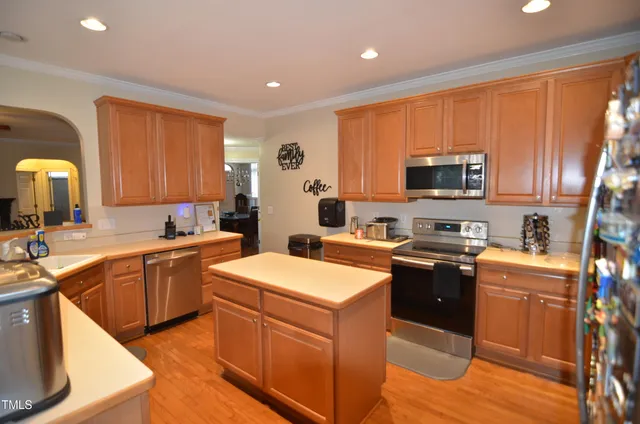 a kitchen with stainless steel appliances kitchen island granite countertop a sink stove and wooden cabinets