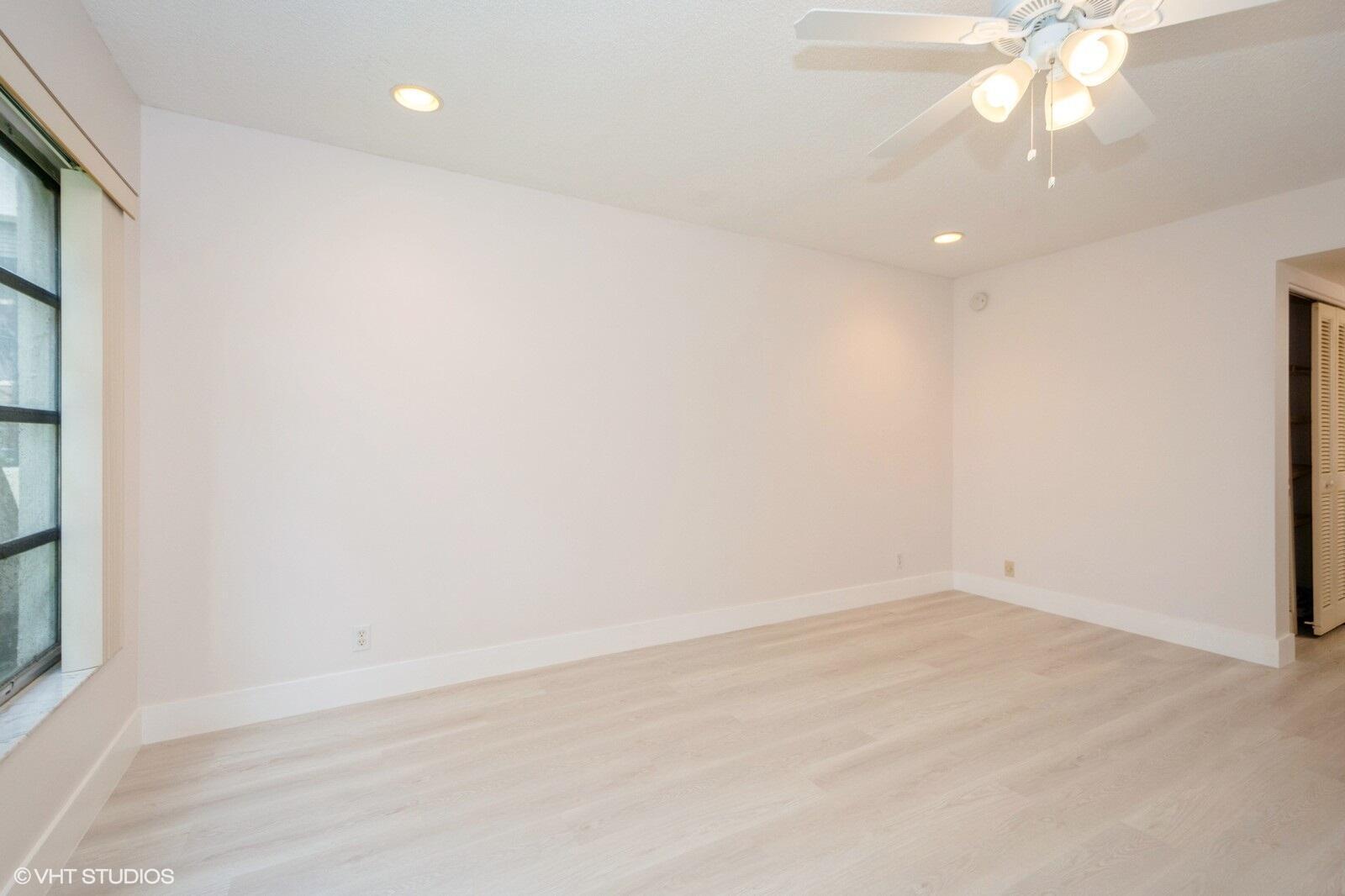10777 West Sample Road, Unit 101 Coral Springs, FL 33065 - Photo 18 of 36 an empty room with a chandelier fan and windows