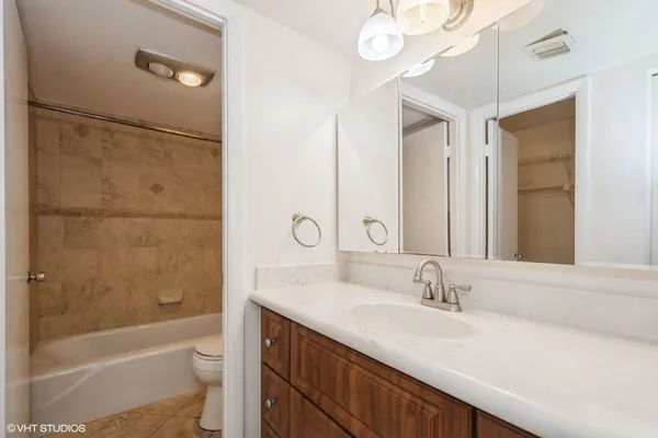 a bathroom with a granite countertop sink a toilet a mirror and shower