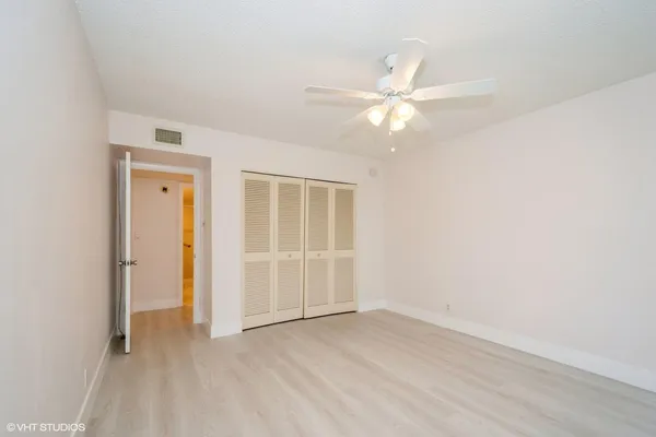 an empty room with closet and a ceiling fan