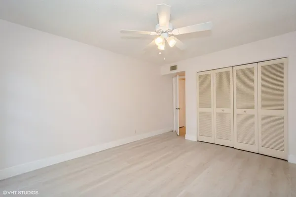 an empty room with a ceiling fan and window