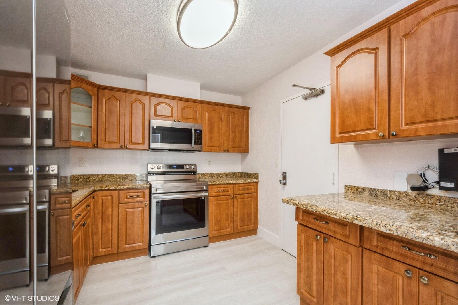 10777 West Sample Road, Unit 101 Coral Springs, FL 33065 - Photo 10 of 36 a kitchen with stainless steel appliances granite countertop a stove top oven a sink dishwasher and a microwave oven with granite countertops