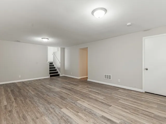 an empty room with wooden floor and natural light
