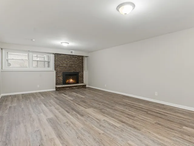 an empty room with wooden floor fireplace and windows
