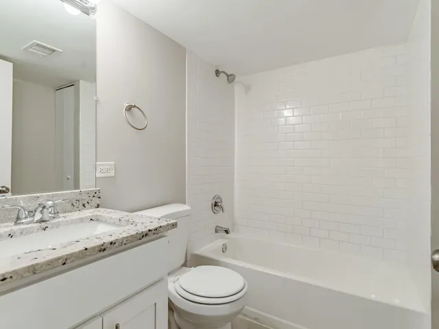 a bathroom with a granite countertop sink a toilet and shower