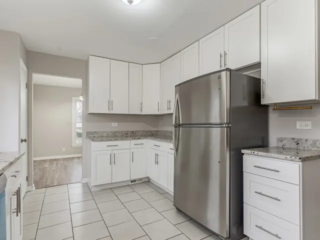 a kitchen with a refrigerator a stove and white cabinets
