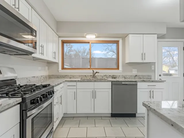 a kitchen with granite countertop a sink stove and cabinets