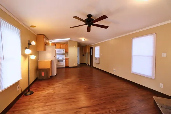 a view of empty room with wooden floor and fan