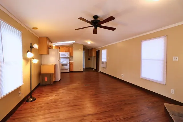 a view of empty room with wooden floor and fan