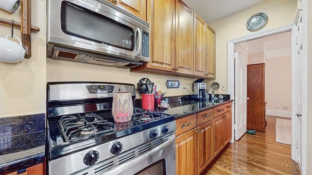 13 Robbins Street, Unit 1 Waltham, MA 02453 - Photo 9 of 29 a kitchen with stainless steel appliances granite countertop a stove and a microwave