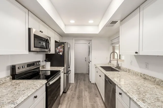 a kitchen with stainless steel appliances granite countertop a sink stove and refrigerator