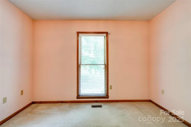 an empty room with chandelier fan and windows