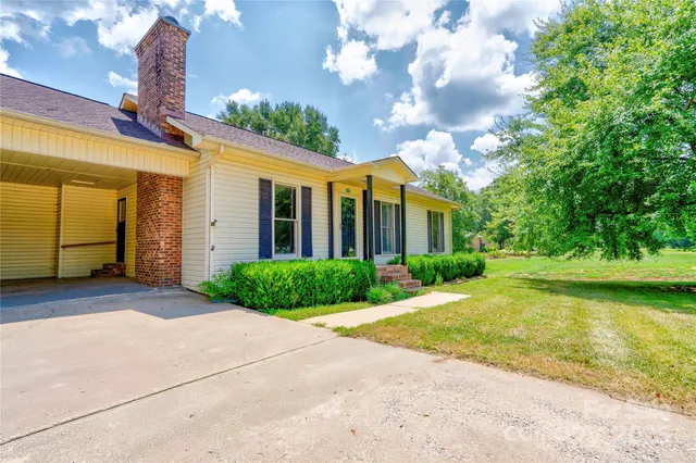 a view of a brick house next to a yard with potted plants