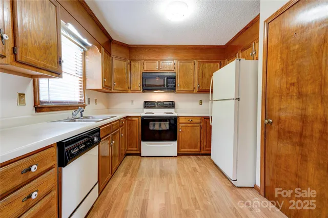 a kitchen with stainless steel appliances granite countertop a refrigerator a sink dishwasher a stove with wooden floor and cabinets