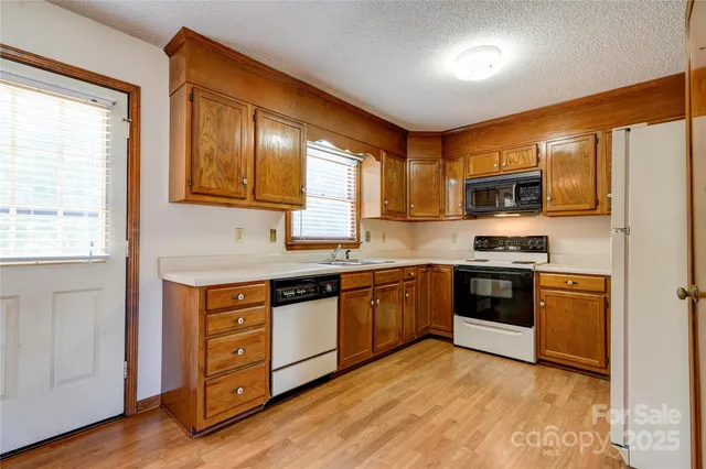 a kitchen with stainless steel appliances granite countertop a stove top oven a sink dishwasher a refrigerator and cabinets with wooden floor