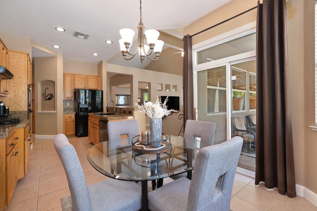 1685 Iroquois Road Rocklin, CA 95765 - Photo 26 of 73 a dining room with wooden floor a chandelier a glass table and chairs