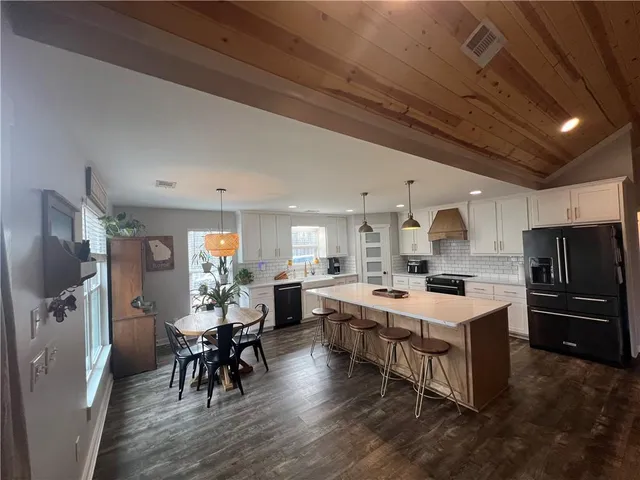 a large kitchen with a table chairs refrigerator and cabinets