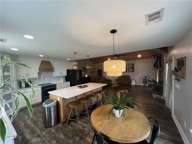 a kitchen with stainless steel appliances a dining table chairs and stove