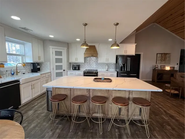 a kitchen with kitchen island a dining table chairs sink and white appliances