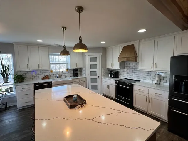 a kitchen with stainless steel appliances kitchen island granite countertop a stove a sink a counter space and cabinets