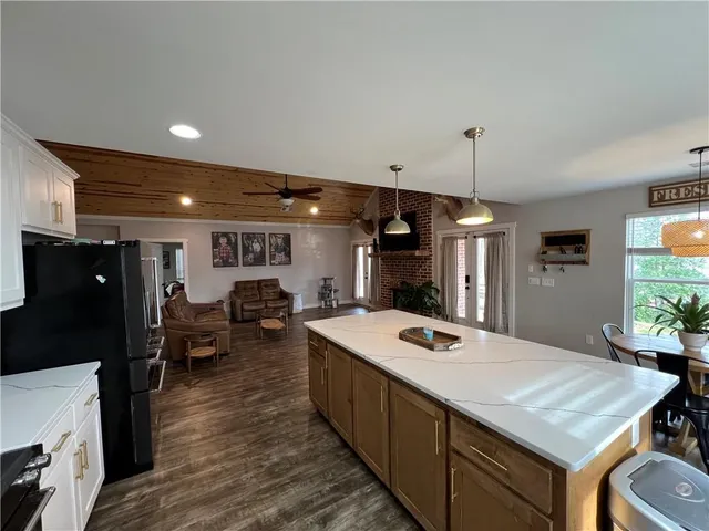 a open kitchen with stainless steel appliances granite countertop a sink dishwasher and a stove with wooden floor