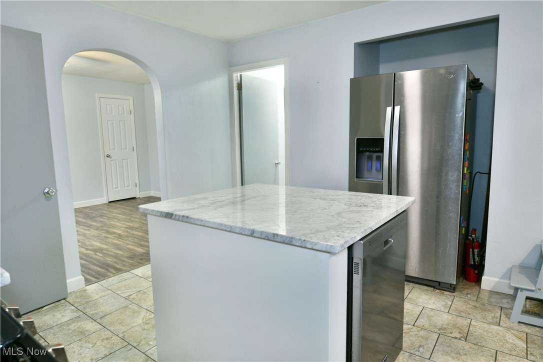 4335 Crew Hood Road Girard, OH 44420 - Photo 21 of 50 Kitchen featuring light stone countertops, a center island, light hardwood / wood-style floors, and stainless steel refrigerator with ice dispenser