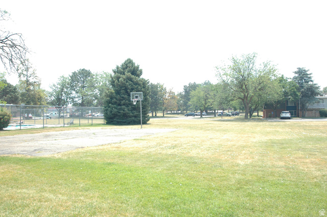 46 Lester Avenue, Unit G 24 Murray, UT 84107 - Photo 4 of 16 Expansive green space featuring a basketball hoop, mature trees, and a fenced swimming pool area