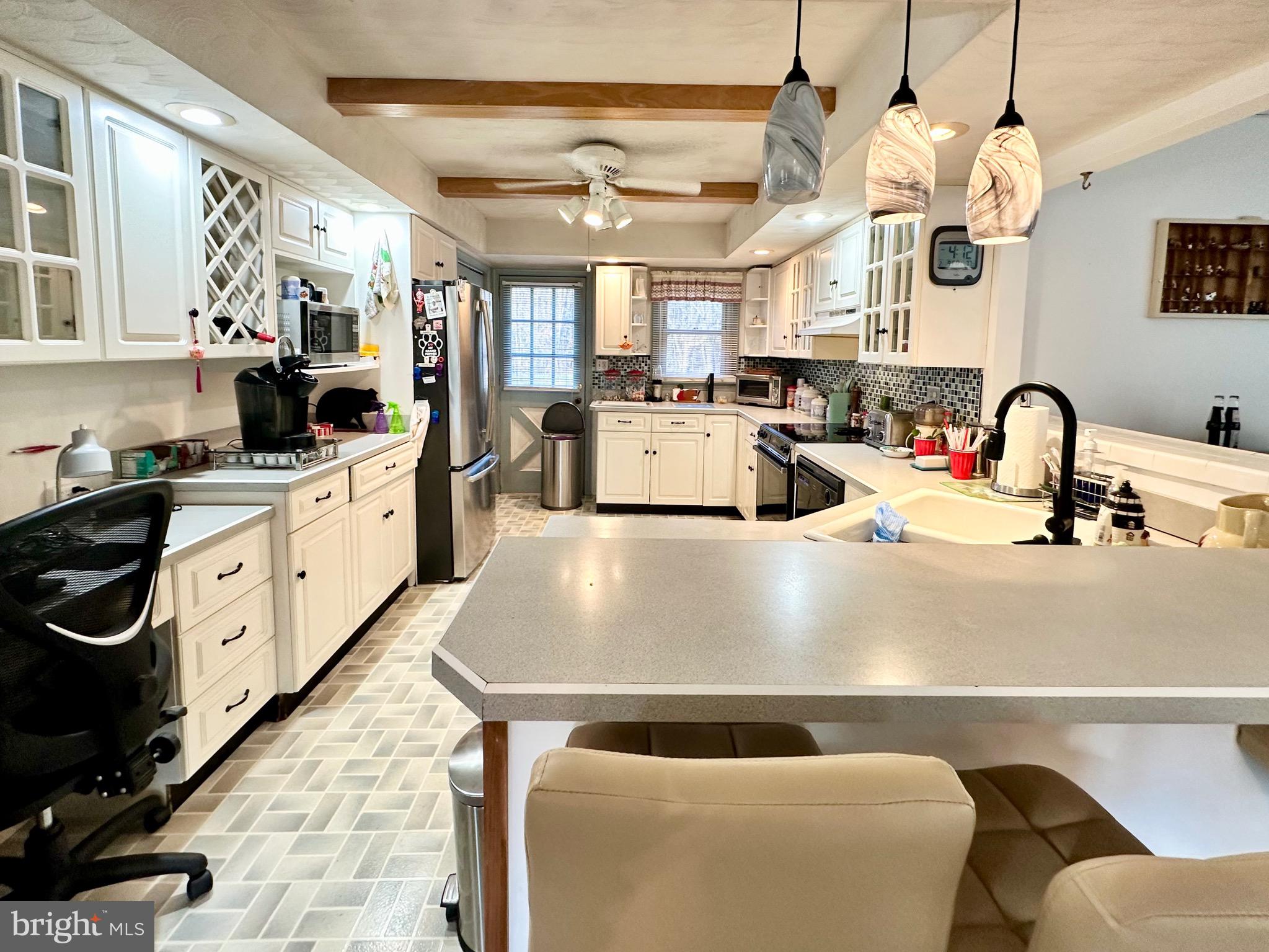 1111 Camp Road Denton, MD 21629 - Photo 22 of 33 a kitchen with stainless steel appliances granite countertop a sink a stove top oven a chimney cabinets and living room view