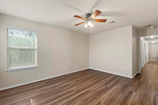 a view of an empty room with wooden floor and a window