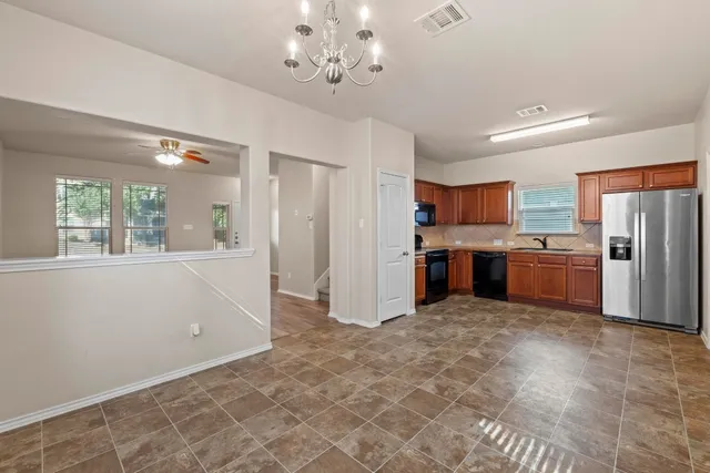 a kitchen with stainless steel appliances granite countertop a refrigerator a stove a sink dishwasher and white cabinets with wooden floor