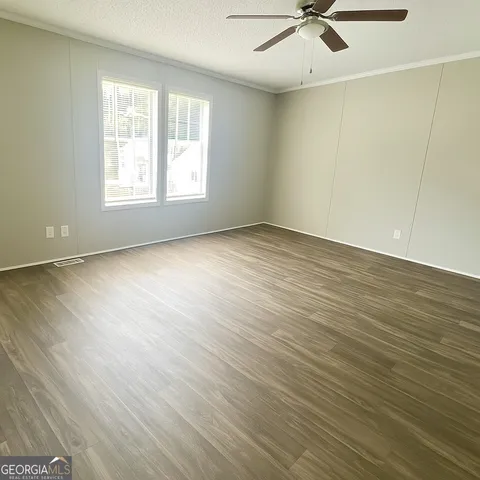 an empty room with wooden floor ceiling fan and windows