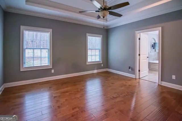 an empty room with wooden floor chandelier fan and windows