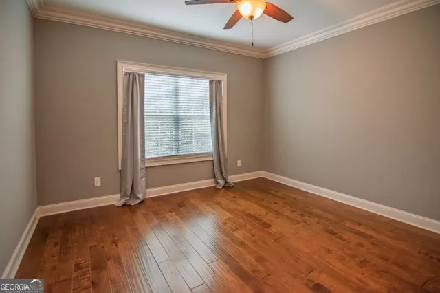 an empty room with wooden floor chandelier fan and windows