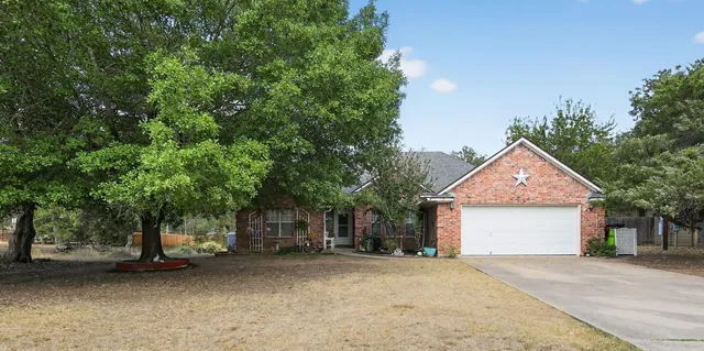 a front view of a house with a garden and trees